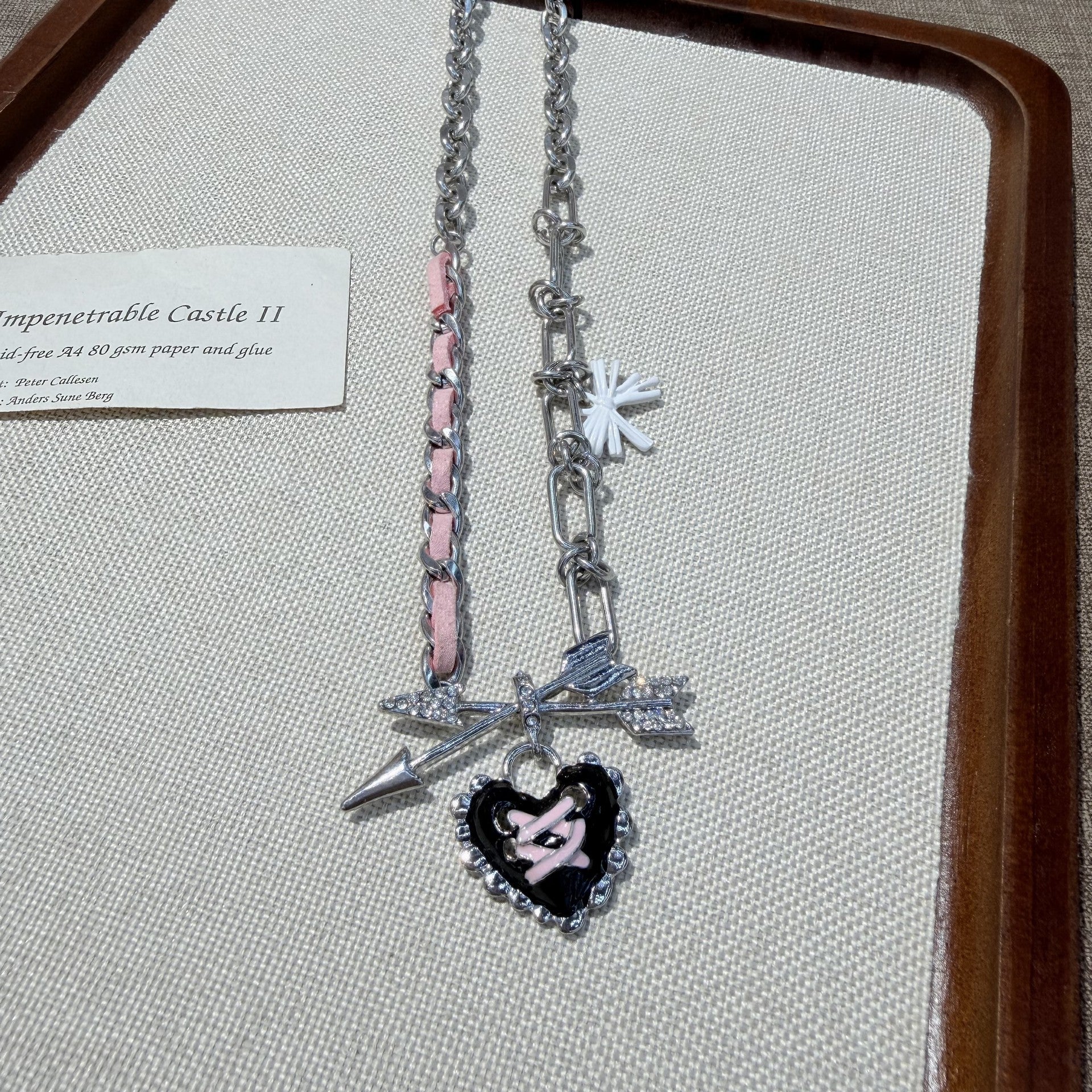 Macro shot of dripping oil heart pendant with cross pattern on pink bow choker
